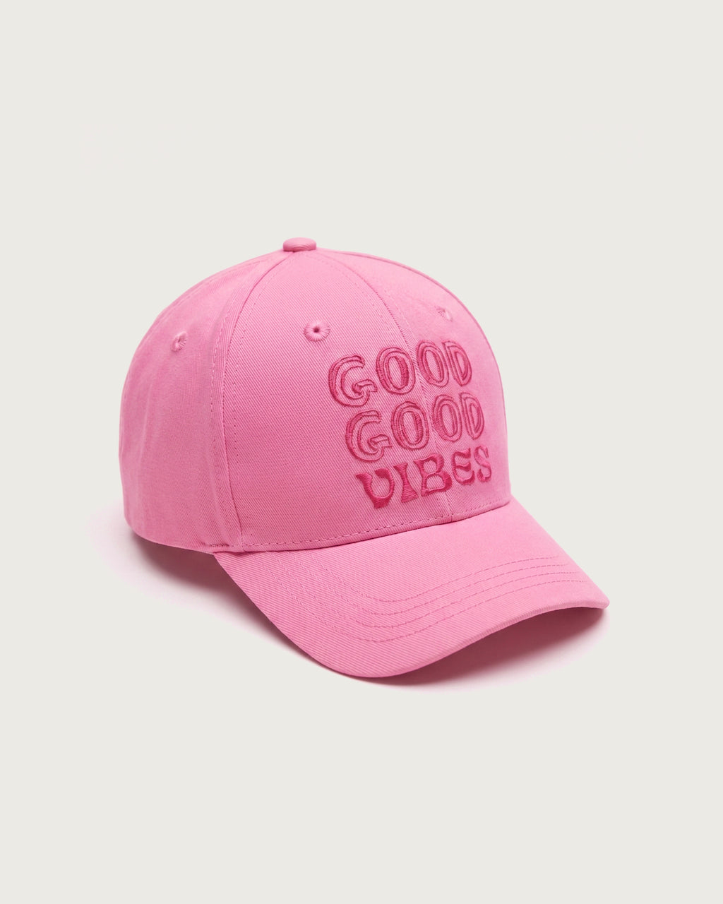 Seitenansicht der rosafarbenen Baseballkappe mit Fokus auf den plastisch hervorgehobenen Stickereien des „GOOD GOOD VIBES“-Schriftzugs und dem leicht gebogenen Schirm.