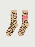Beige Crew-Socken mit Leopardenmuster in Braun und Schwarz. Auf einer Socke befindet sich ein pinker Kreis mit der Aufschrift „MAMA GEHT TANZEN“. Beide Socken sind frontal auf hellgrauem Hintergrund dargestellt.